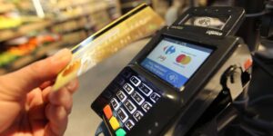 Main approchant une carte bancaire d’un terminal de paiement sans contact dans un commerce.