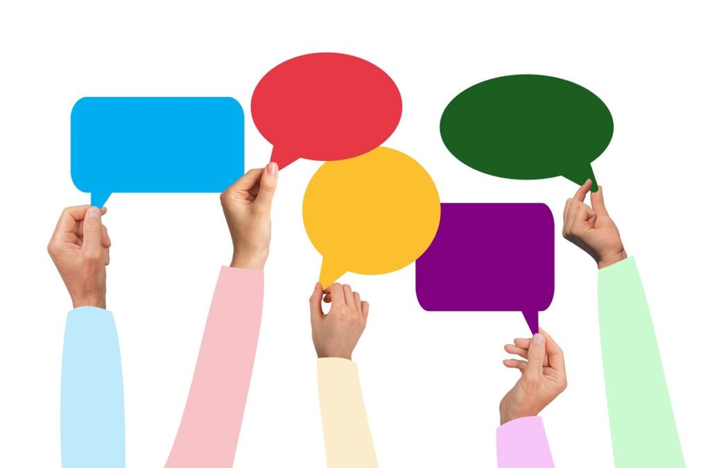Mains tenant des bulles de dialogue colorées, symbolisant la diversité des opinions exprimées dans un sondage