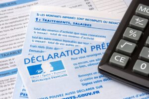 Gros plan sur des formulaires fiscaux français « Déclaration préremplie » avec une calculatrice, illustrant le calcul de l’impôt sur le revenu et la régularisation.