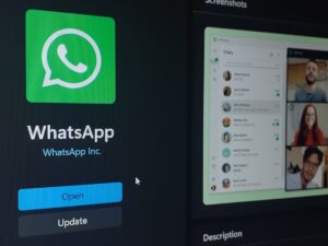 Écran d’ordinateur affichant la page de téléchargement de WhatsApp avec les boutons « Open » et « Update » et un aperçu de conversations et d’un appel vidéo.